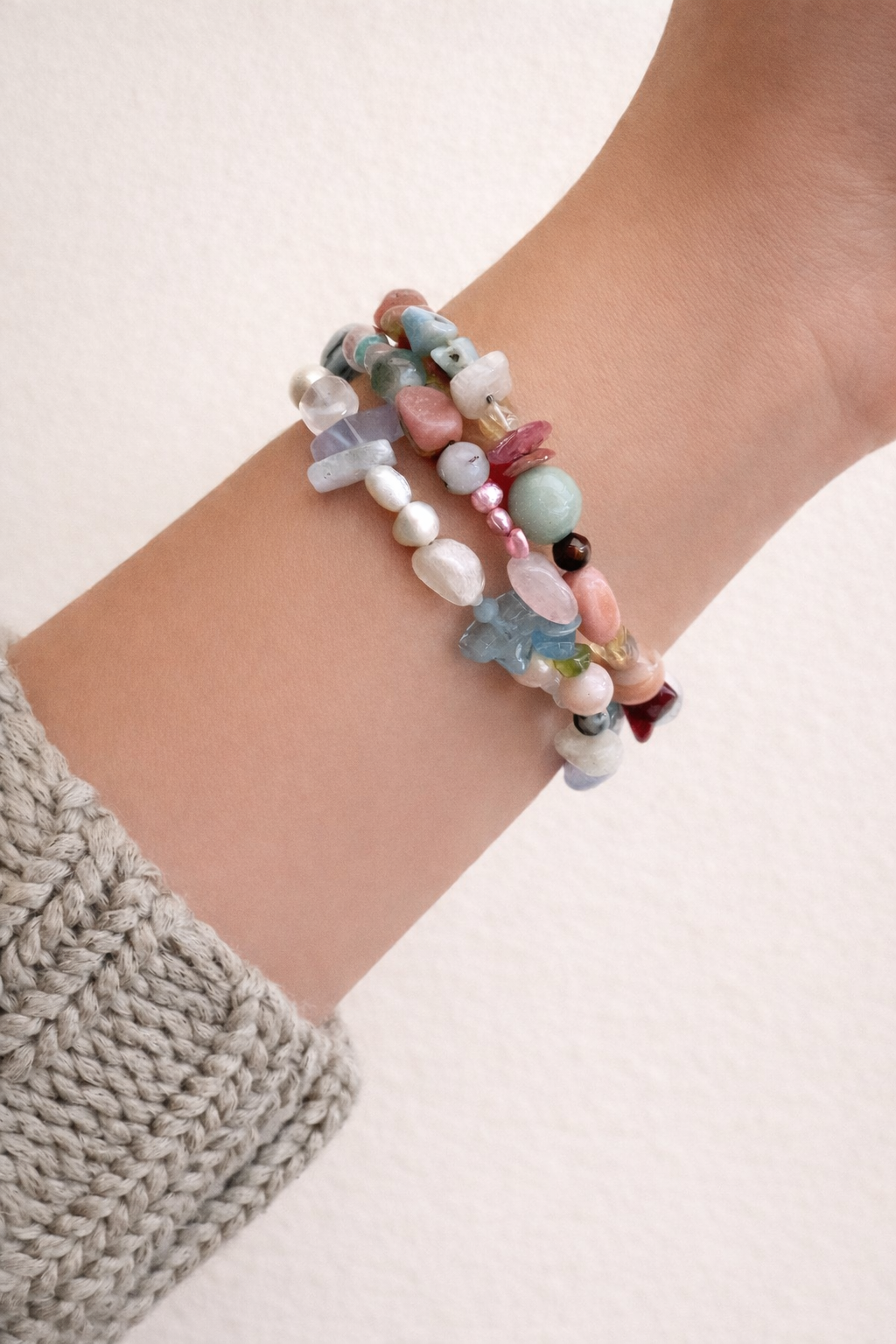 Multicolored crystal beaded bracelets on a wrist with a neutral background