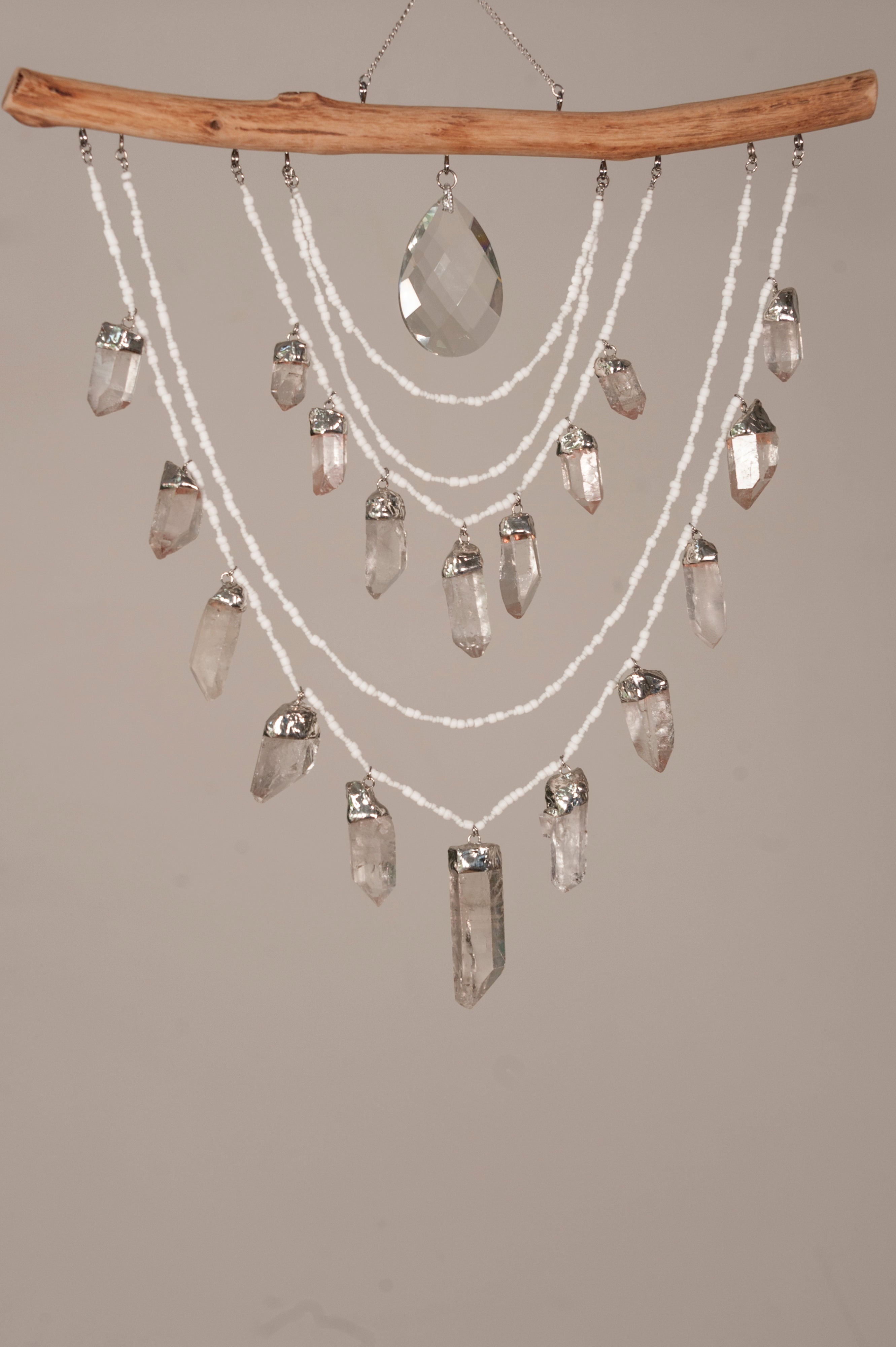 Crystal chandelier with clear crystals and a wooden branch on a gray background
