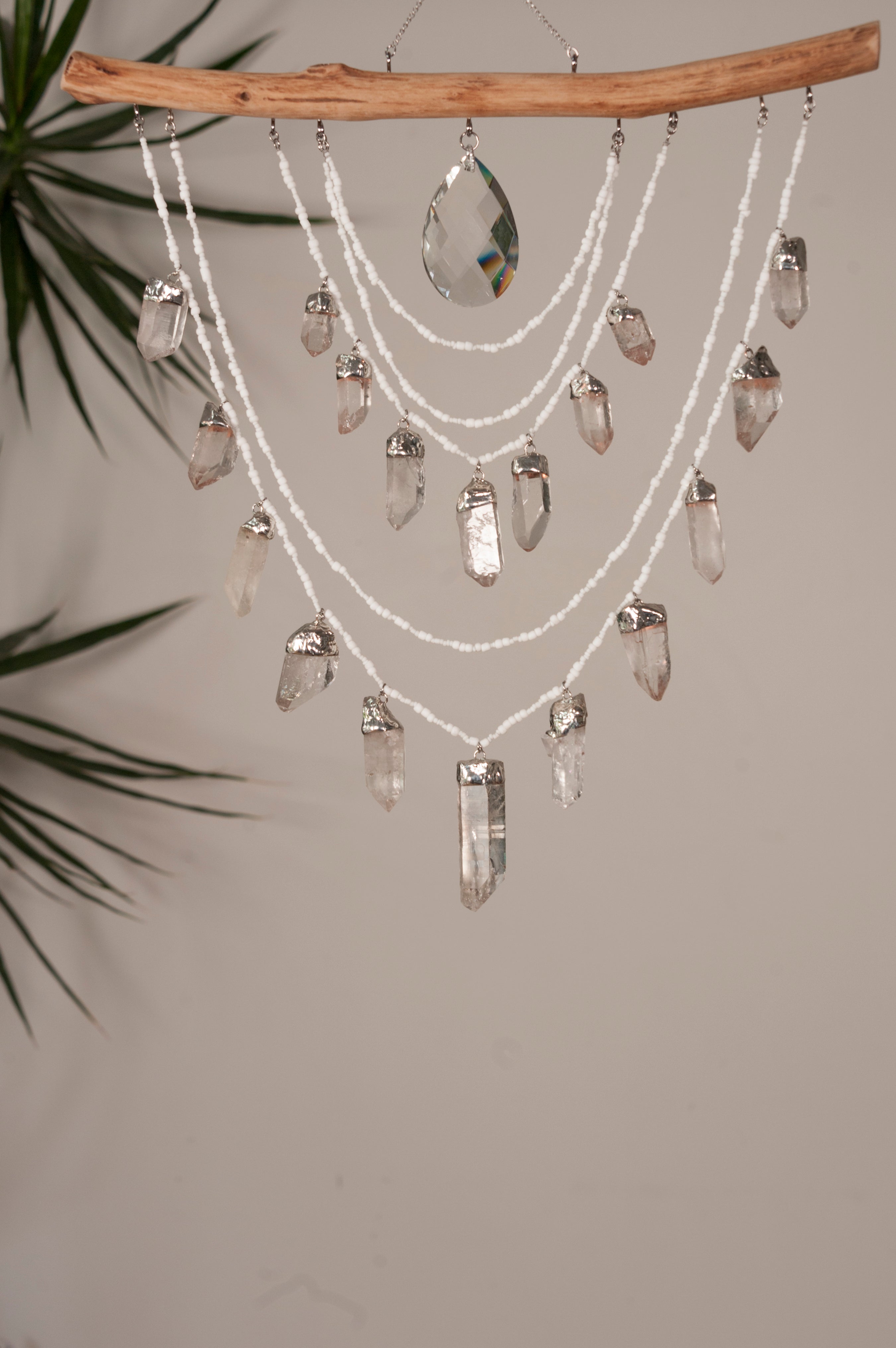 Crystal chandelier hanging from a branch with a neutral background