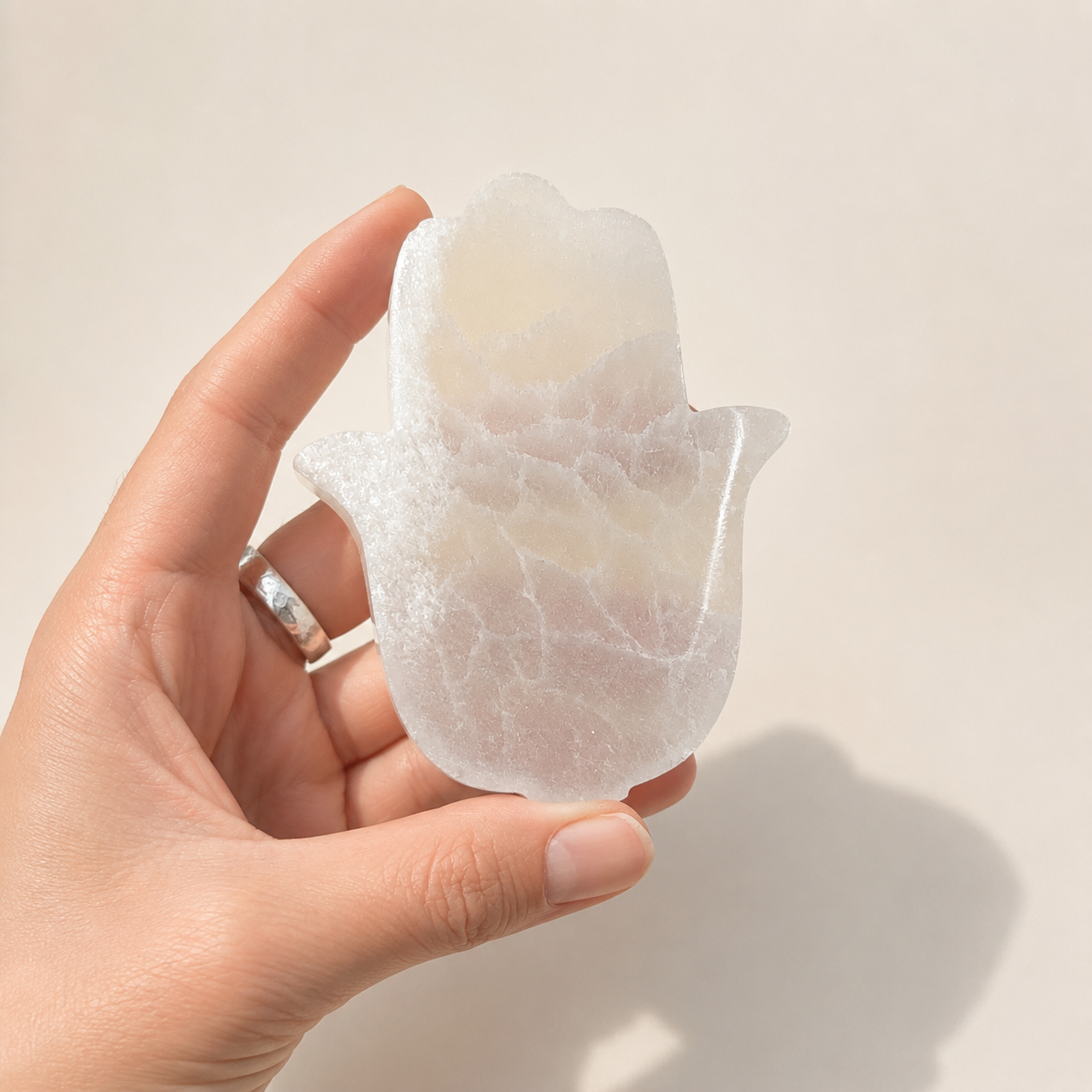hand holding selenite hamsa hand